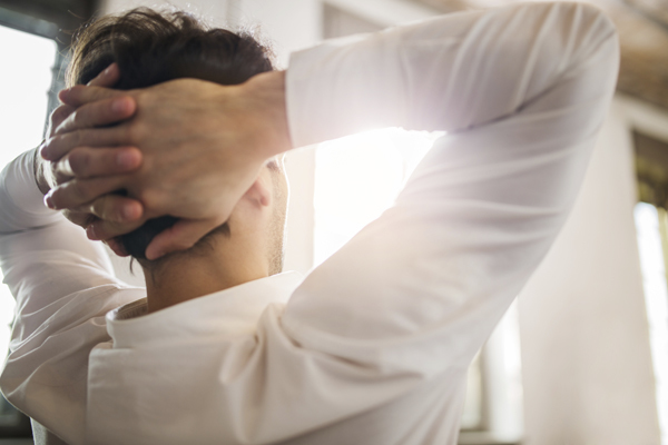 Rear view of a relaxed man with hands behind his head.